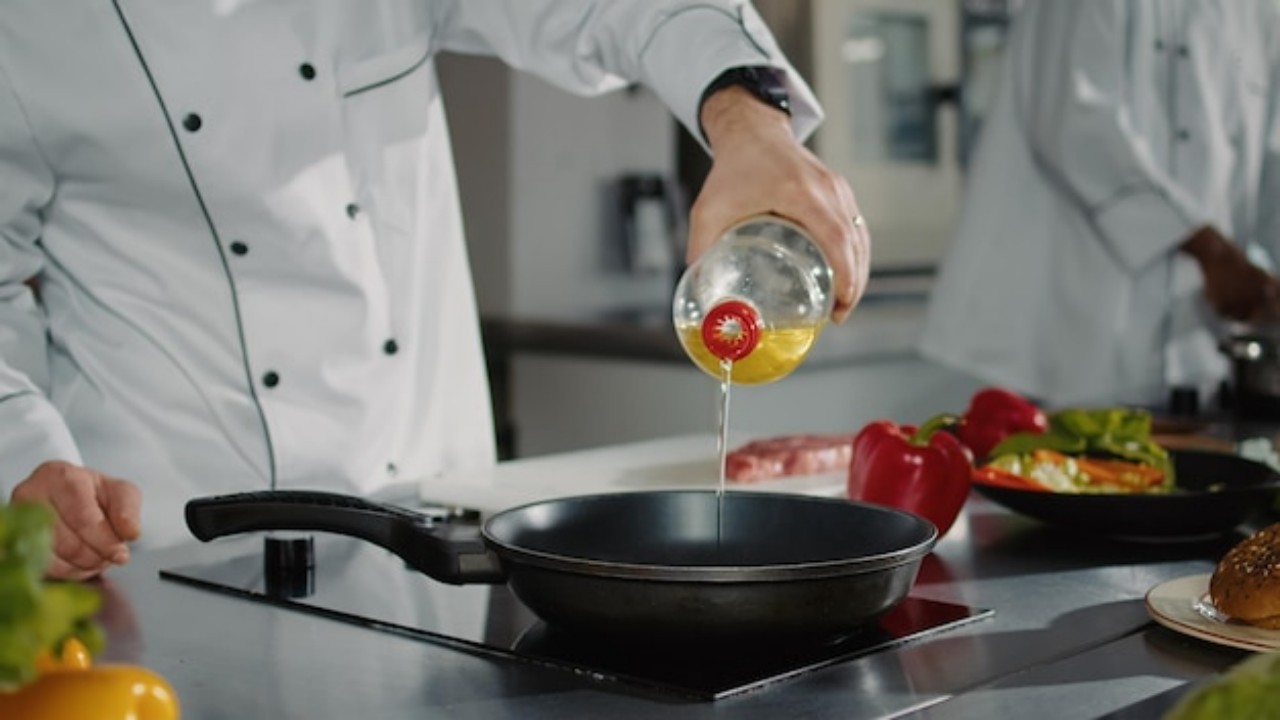 Male chef pouring oil from a bottle