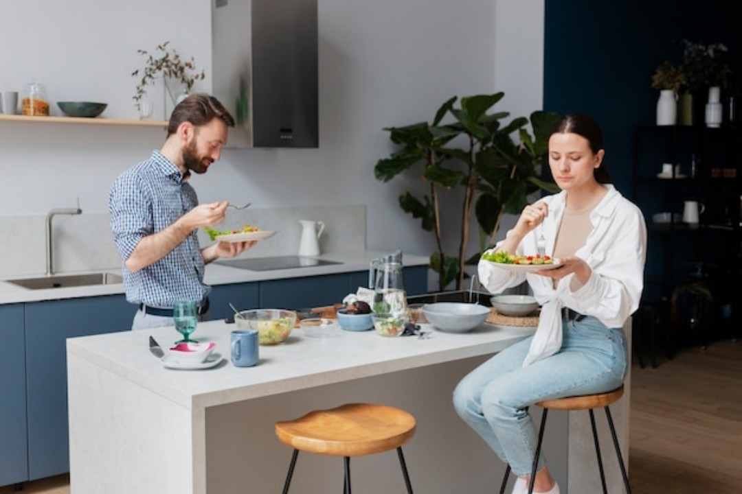 couple sitting around a table, enjoying a meal together.